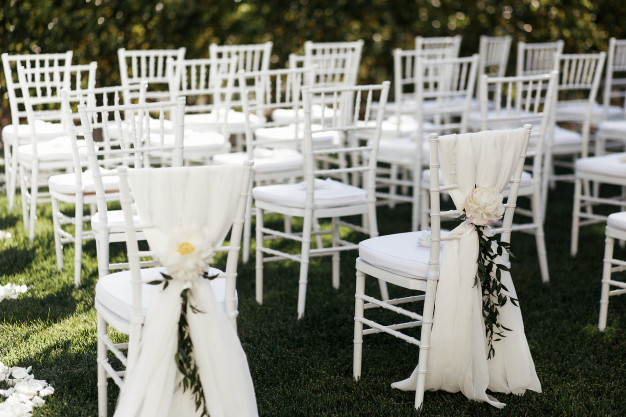 Cadeiras brancas de casamento sobre um tapete de grama sintética